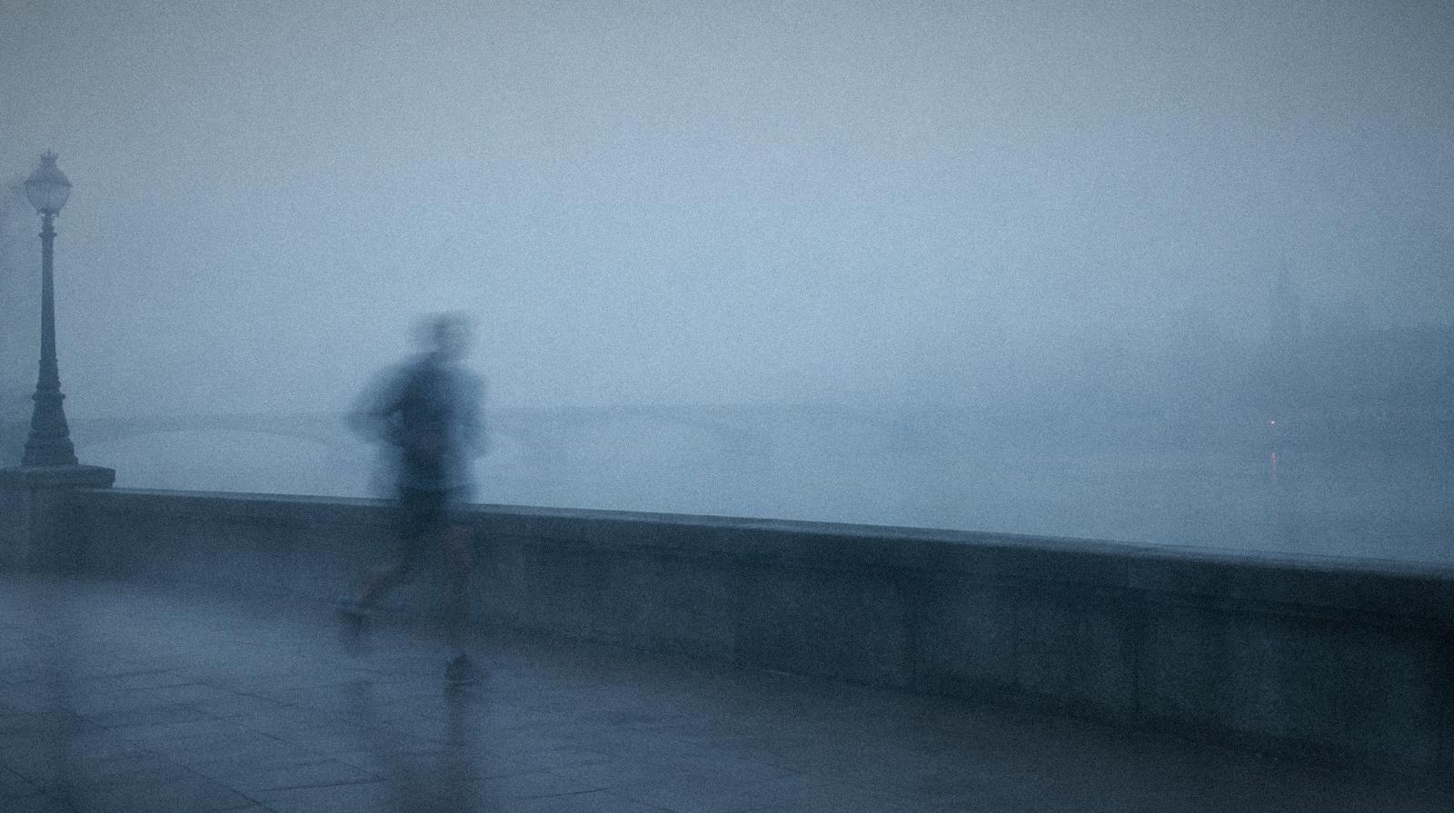 A runner on the Thames path in dawn mist