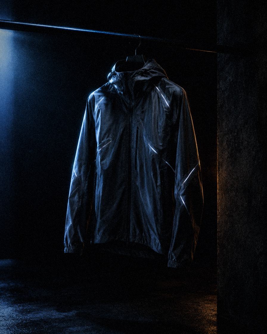 A gunmetal running jacket hanging in a dark room
