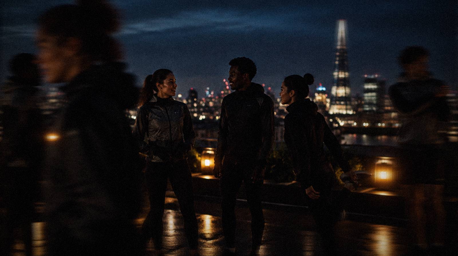 Members chatting on a rooftop above London at night